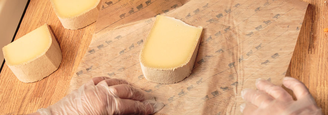 This is a picture of a Fromagination cheesemonger wrapping cheese.