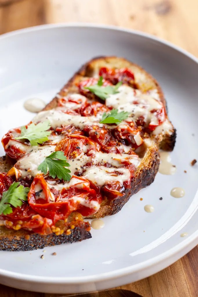 toasted sourdough bread topped with roasted cherry tomatoes and drizzled with tahini