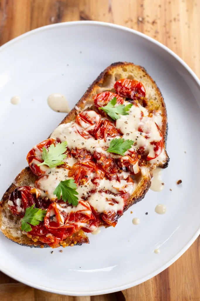 toasted sourdough bread topped with roasted cherry tomatoes and drizzled with tahini