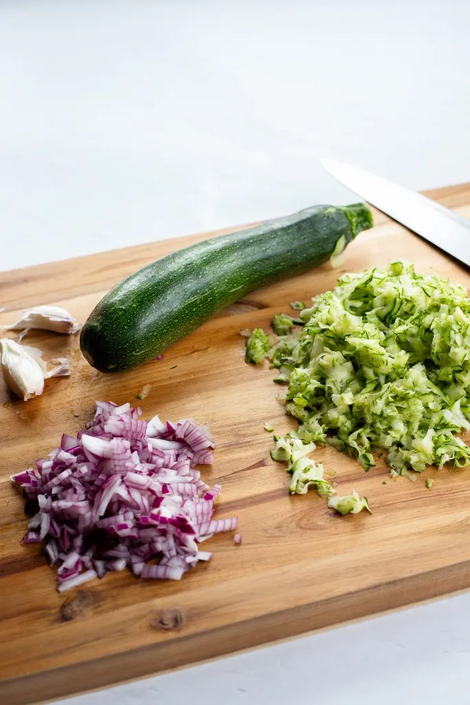ingredients for creamy zucchini pasta on a cutting board.
