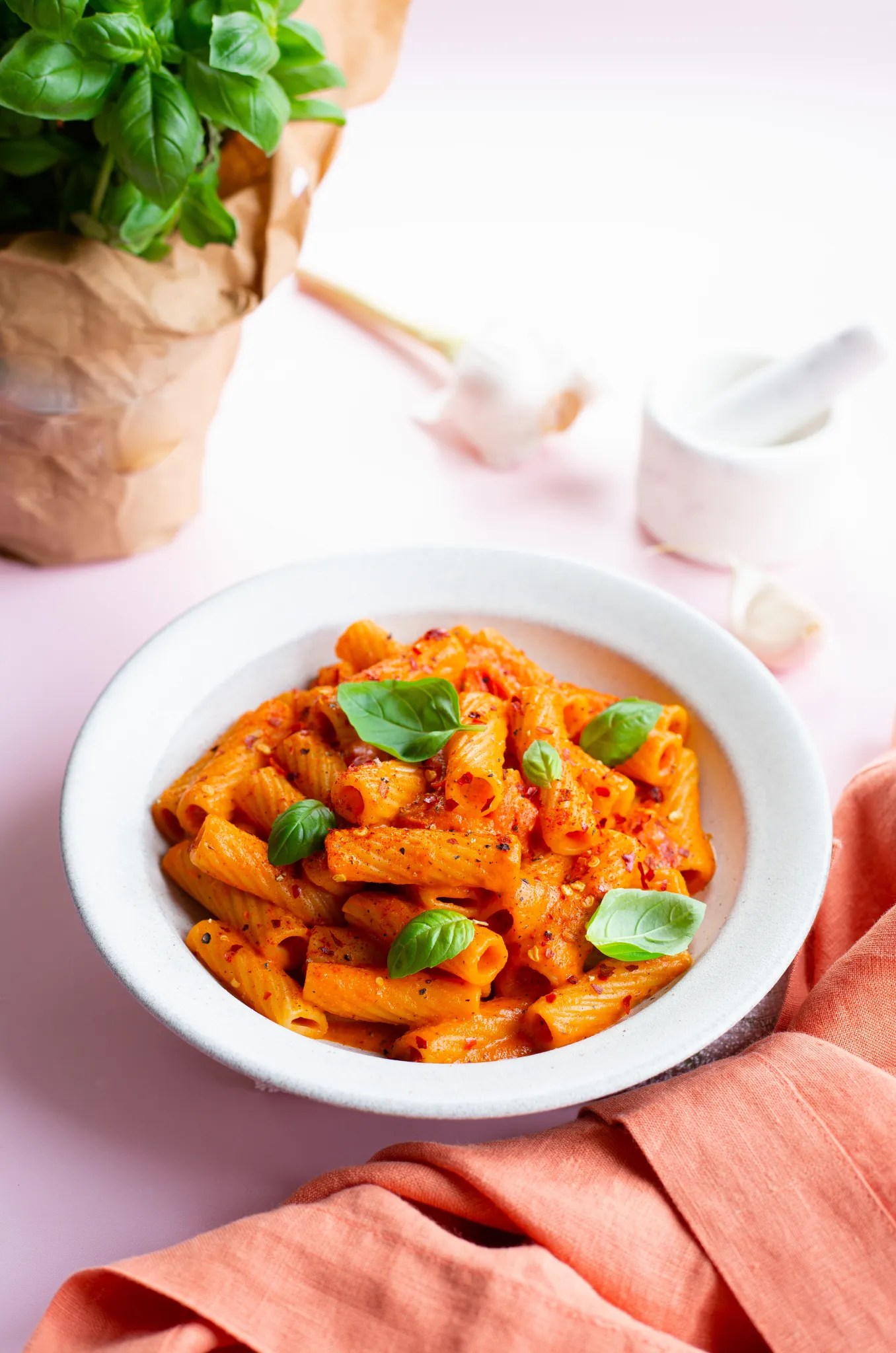 creamy roasted red pepper pasta in bowl with basil