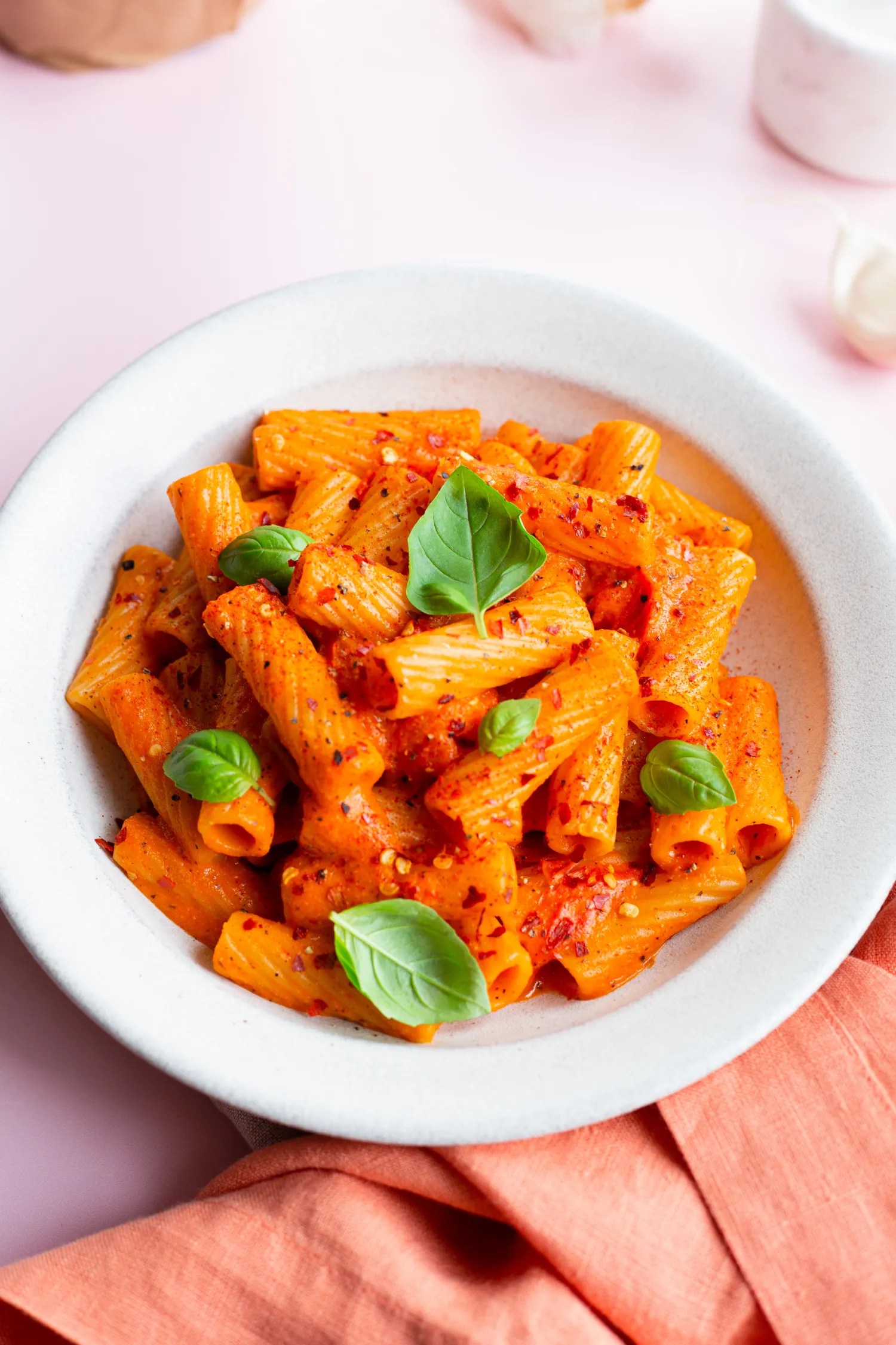 creamy roasted red pepper pasta in bowl with basil