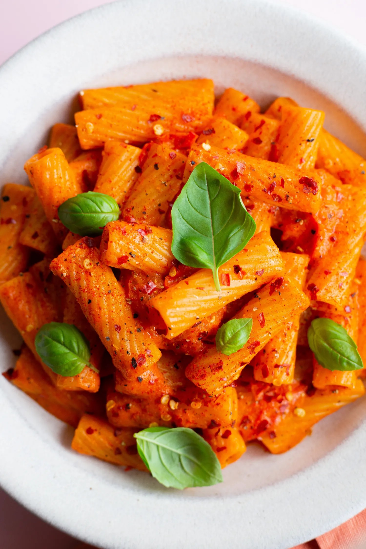 creamy roasted red pepper pasta in bowl with basil