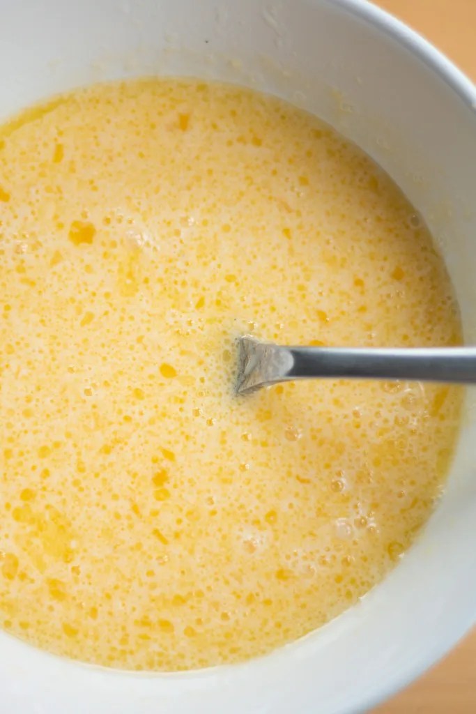 Whisking buttermilk, melted butter, vanilla, and an egg together in a medium mixing bowl.