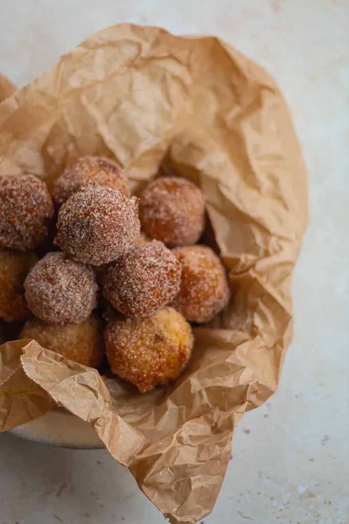 Freshly fried buttermilk donut holes on parchment paper