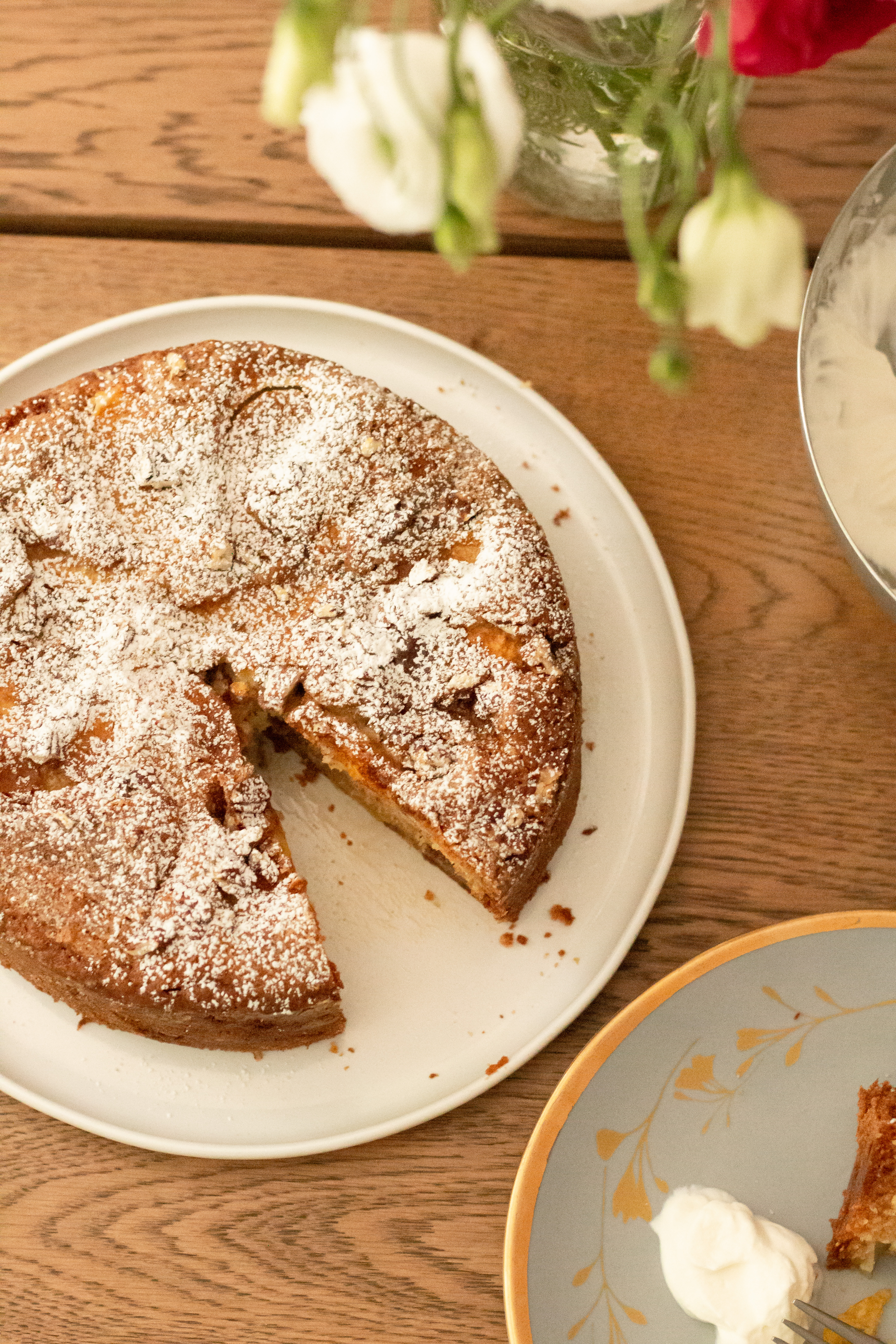 fresh peach cake on a serving platter dusted with icing sugar