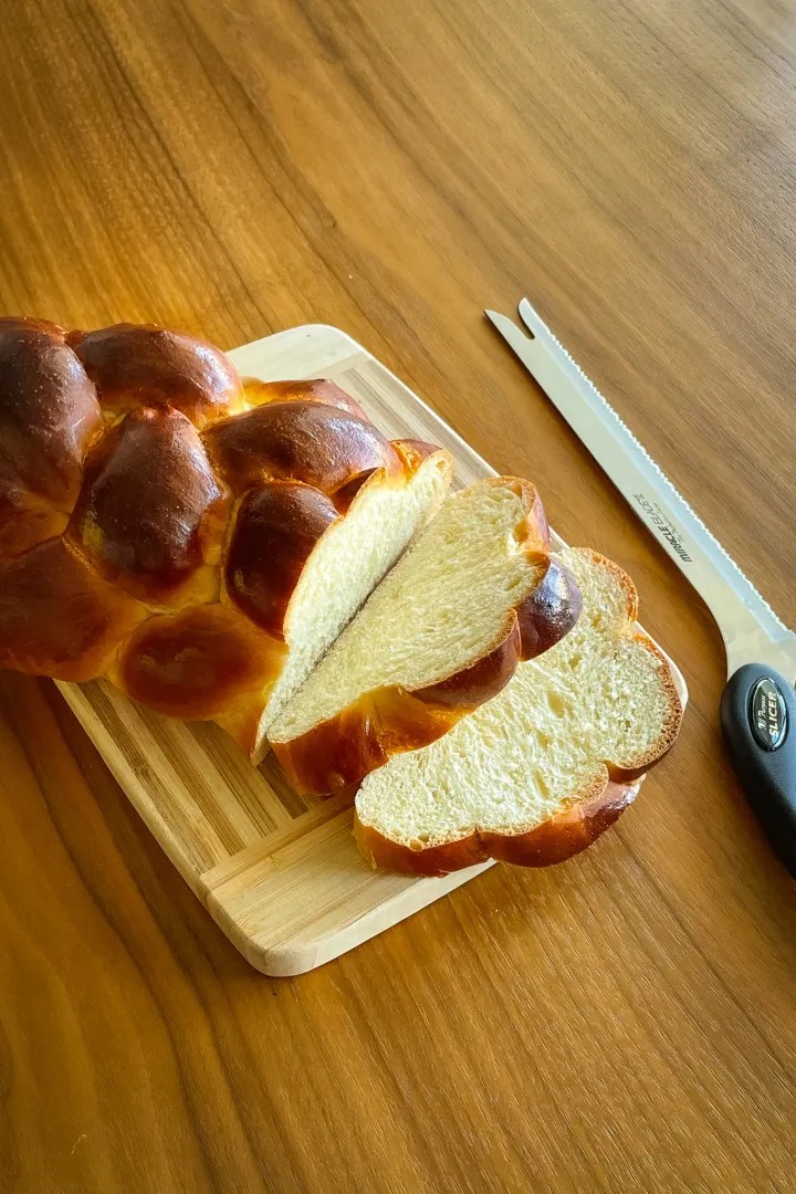 sliced homemade challah bread served on a wood cutting board
