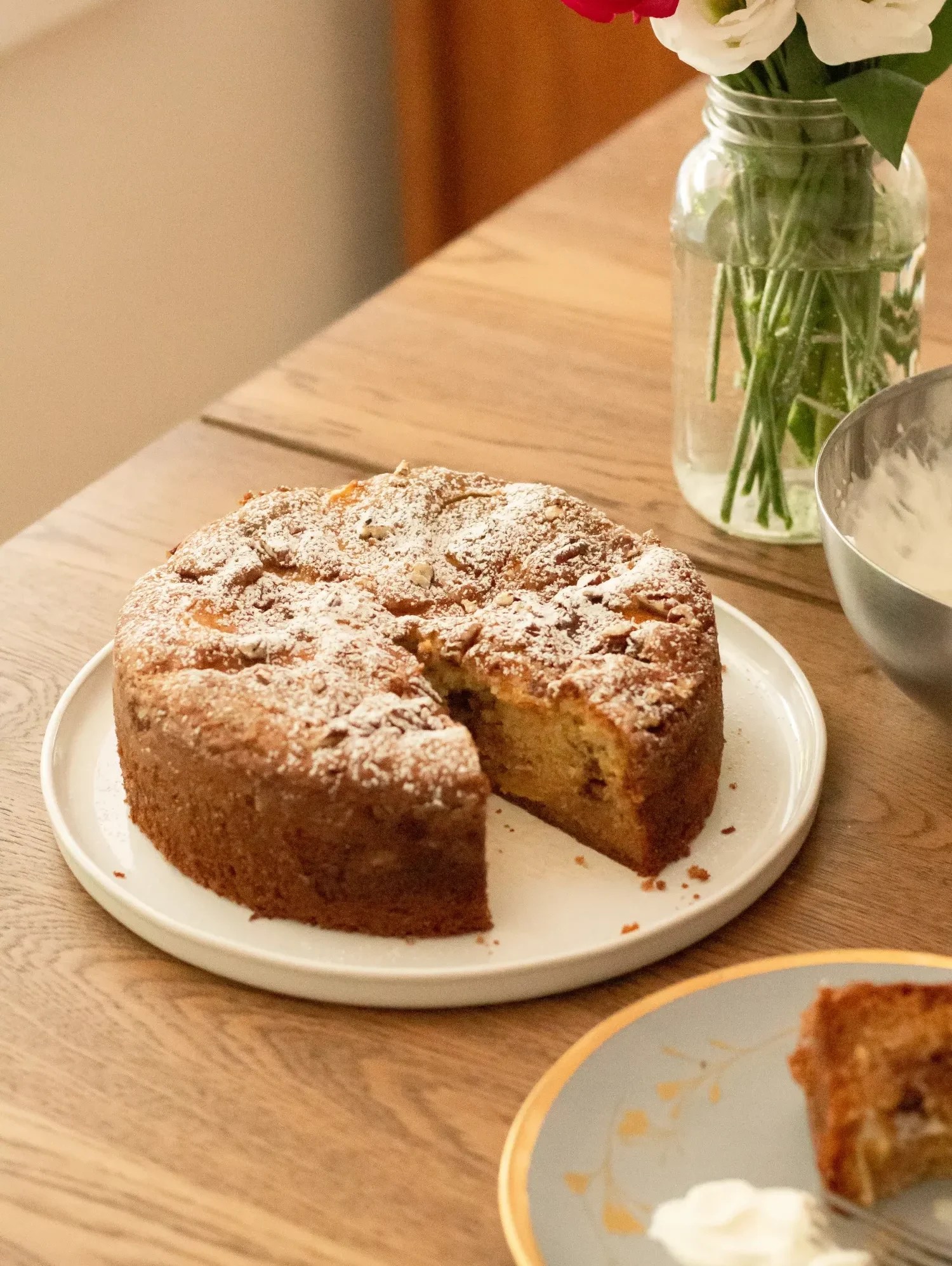 fresh peach cake dusted with icing sugar on a serving platter