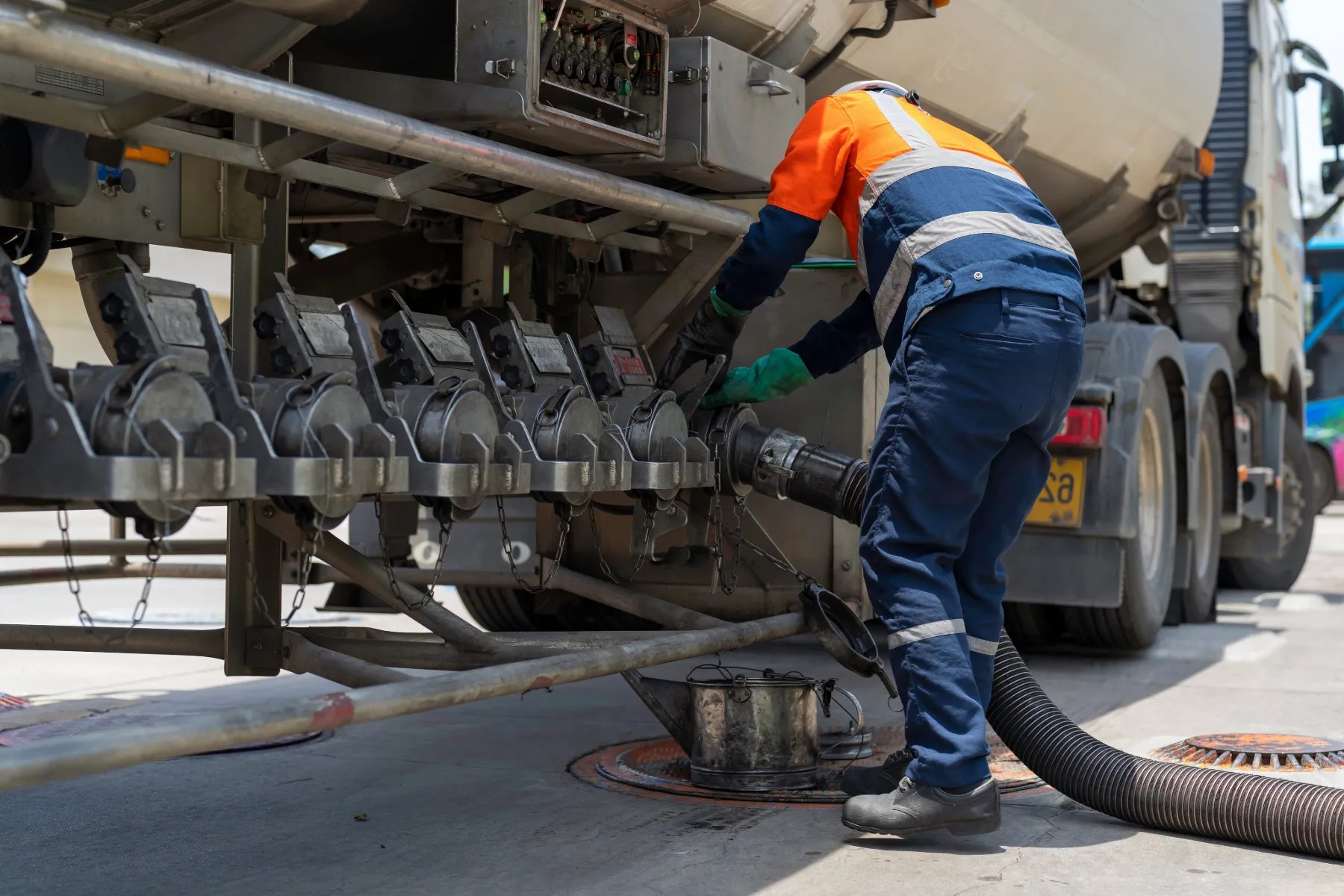 Fuel delivery driver operating hoses on a commercial tanker truck