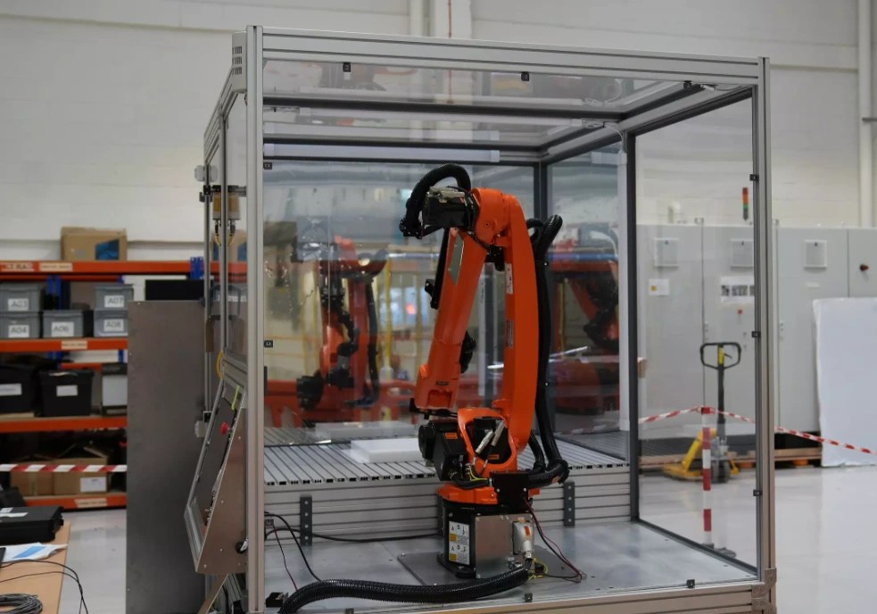 An orange Kuka industrial robotic arm mounted inside a transparent test enclosure as part of UKAEA Partnership Project P170, the Fusion Oriented Robotic Technology programme developing radiation tolerant robotics for STEP and EU-DEMO remote maintenance.
