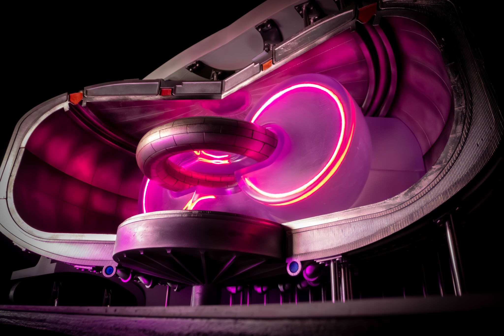 Interior view of a levitated dipole fusion device showing a glowing magenta plasma confined around a ring-shaped superconducting core magnet inside a vacuum vessel.