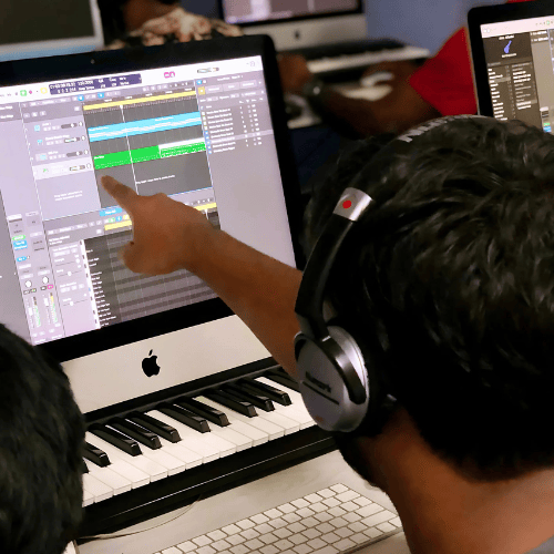 A music production student of Future School of Performing Arts using headphones pointing at the screen, where DAW software is in use.