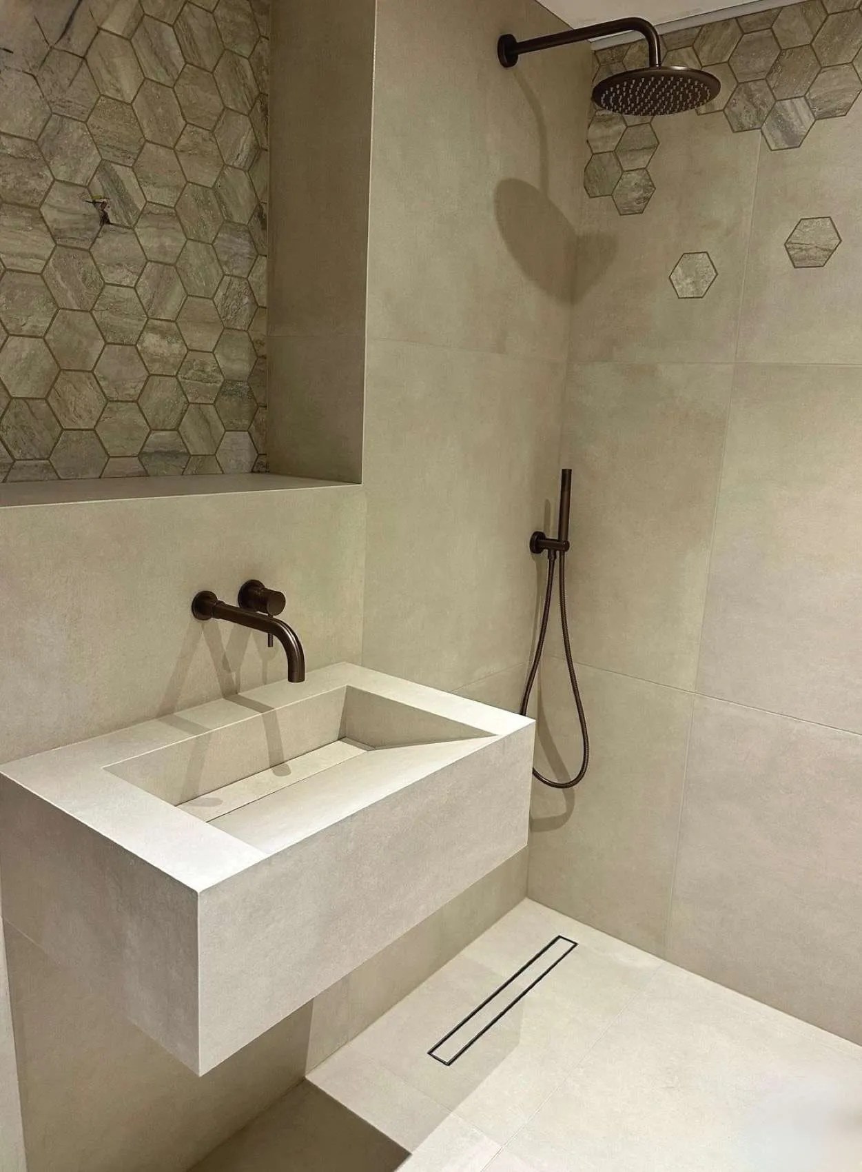Close-up of contemporary bathroom shower with stylish sink, minimalist fixtures, and hexagon wall tiles.