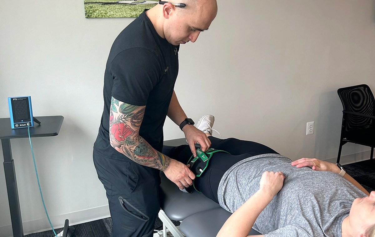 Physical therapist applying a blood flow restriction cuff to a patient's leg