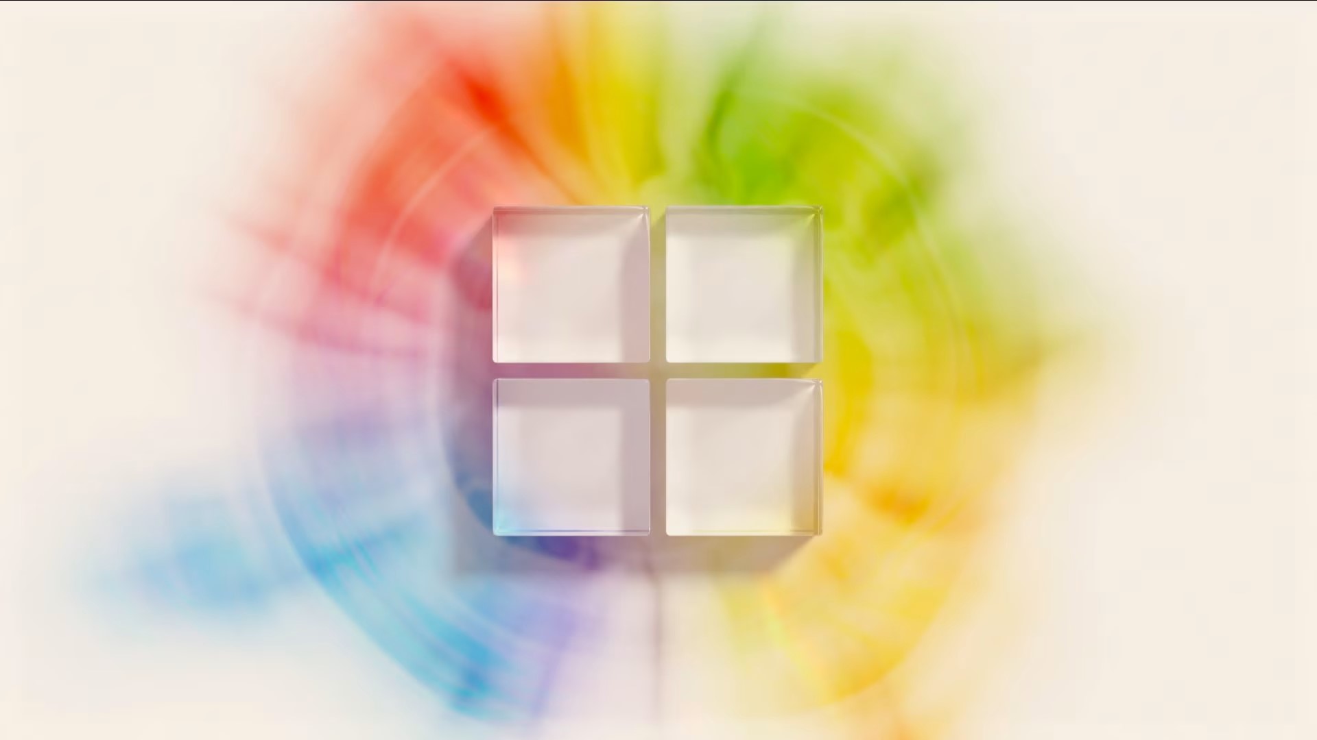 A colorful 3D rendering of the Microsoft logo. The logo consists of four squares with rounded corners arranged in a square formation. The top-left square is colored red, the top-right square is colored green, the bottom-left square is colored blue, and the bottom-right square is colored yellow. A colorful rainbow wraps around the four squares.