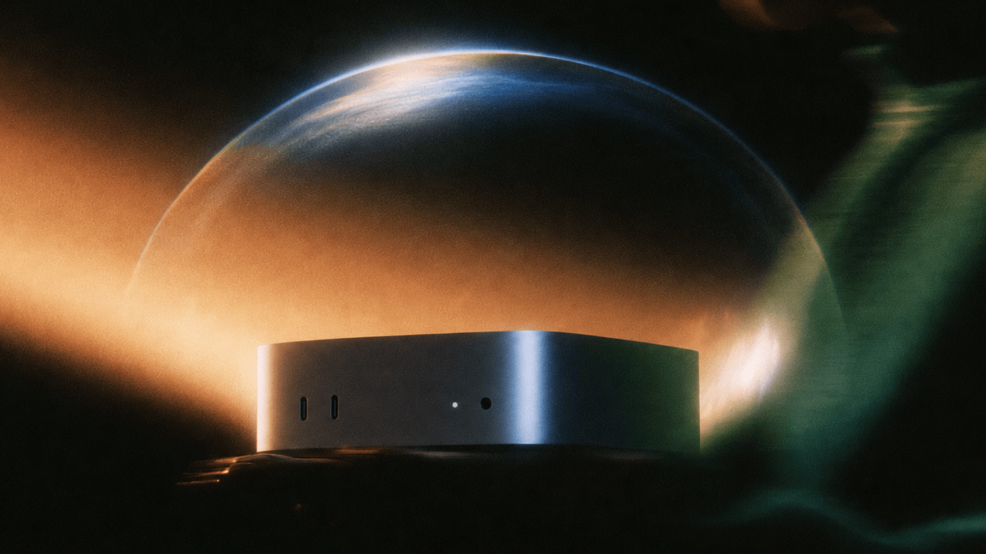 Silver Mac mini device resting in front of a glowing, curved planetary sphere in dark space.