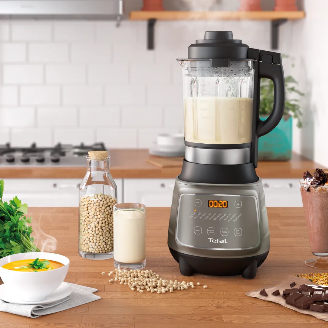 Tefal DynamiX Cook 攪拌機杯內煮好嘅豆漿，枱面放住黃豆同五穀