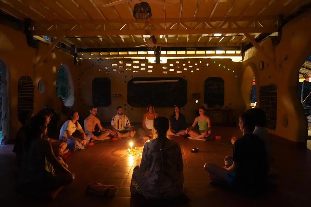 People sitting in circle meditating calmly in a low lit sala