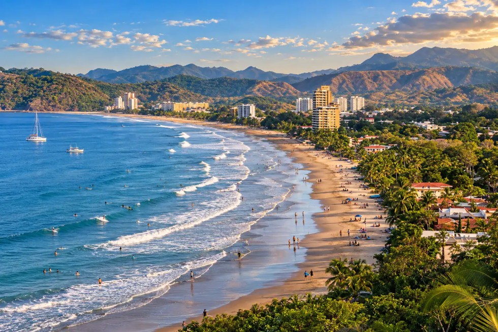 Jacó beach from above at sunset, the bay curving past the condominium towers