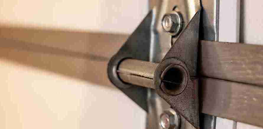 Close-up of a broken garage door hinge and track system, highlighting the need for garage door repair and maintenance services.