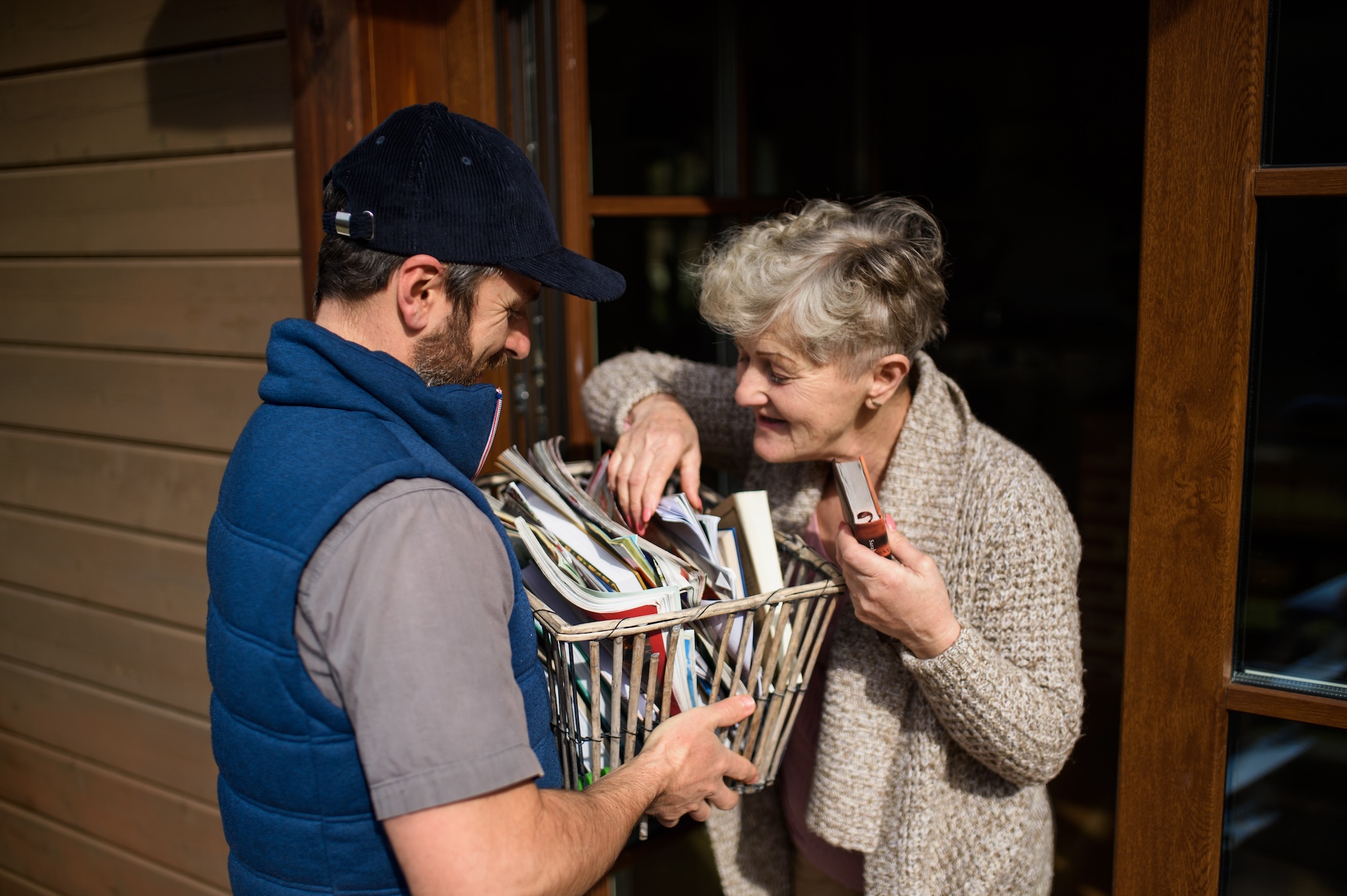 Man courier delivering books and magazines to senior woman.