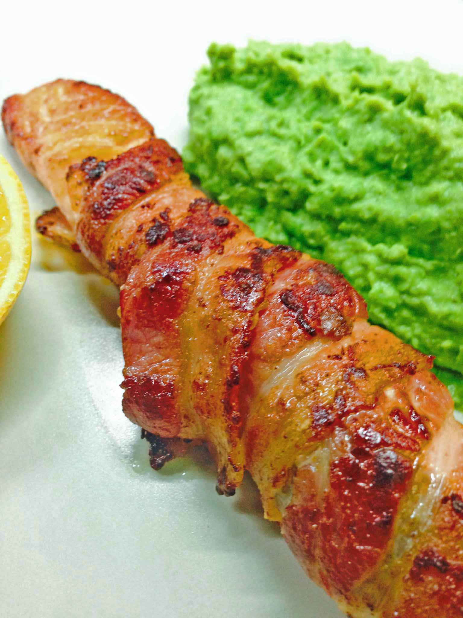 Salmon wrapped with streaky bacon and served with mushy peas