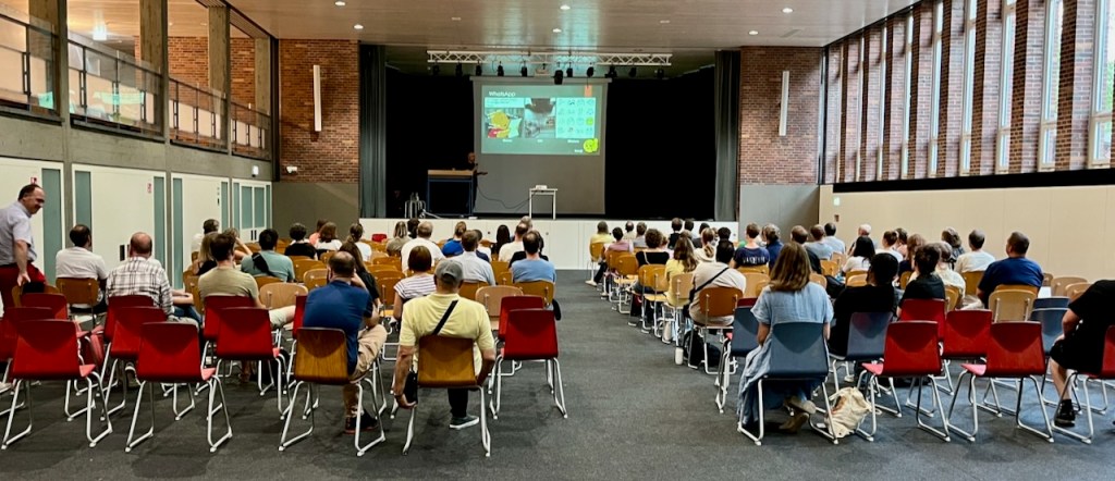 Die Turnhalle der GBS mit belegter Bestuhlung und der Präsentation auf der Bühne