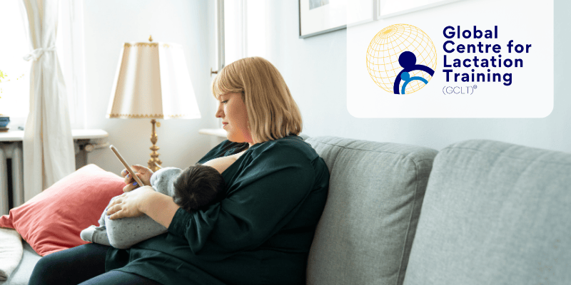 Photo of person sitting on sofa while breastfeeding baby and looking at phone