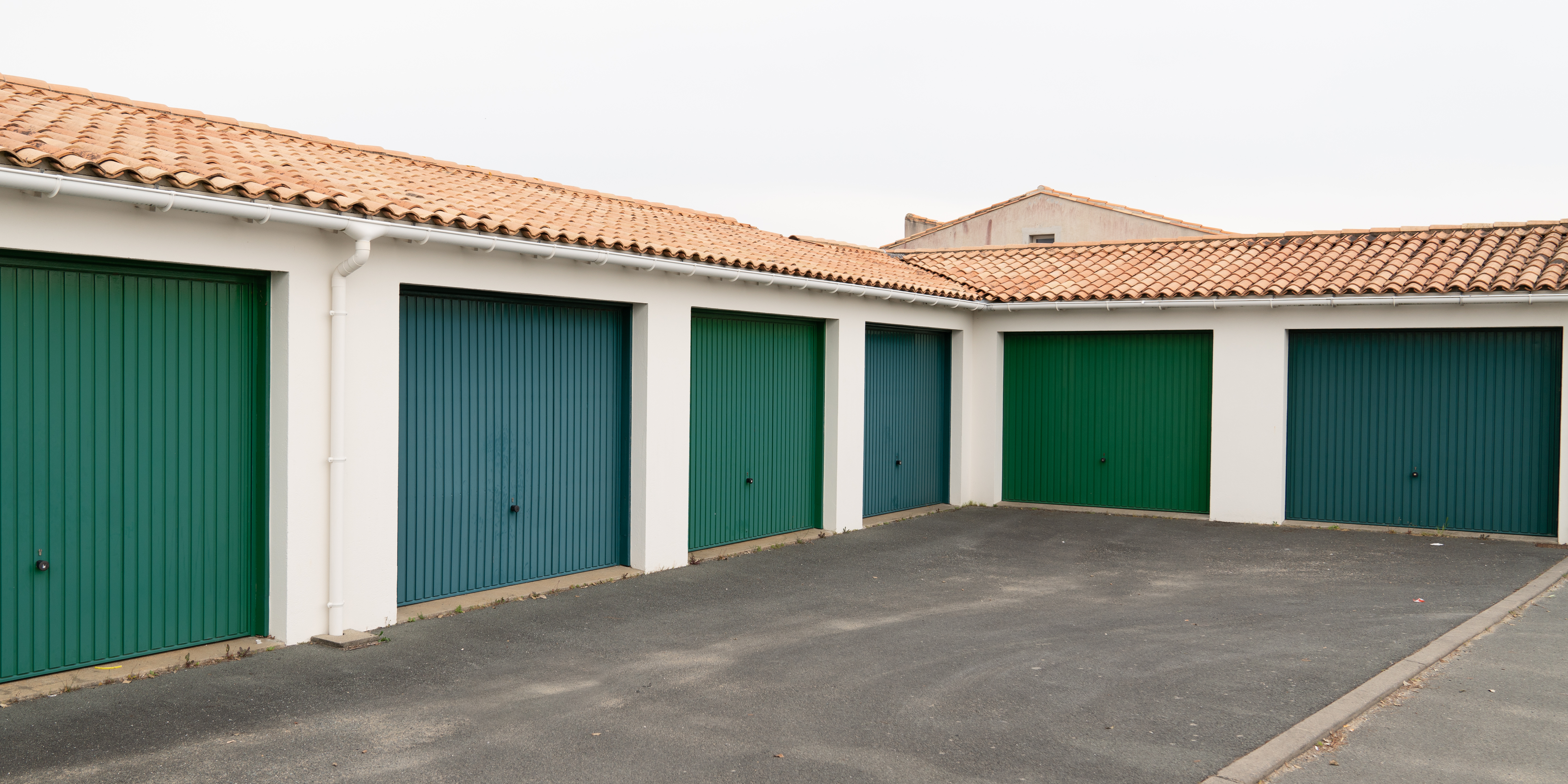 row of green parking garage doors in parking area for apartment