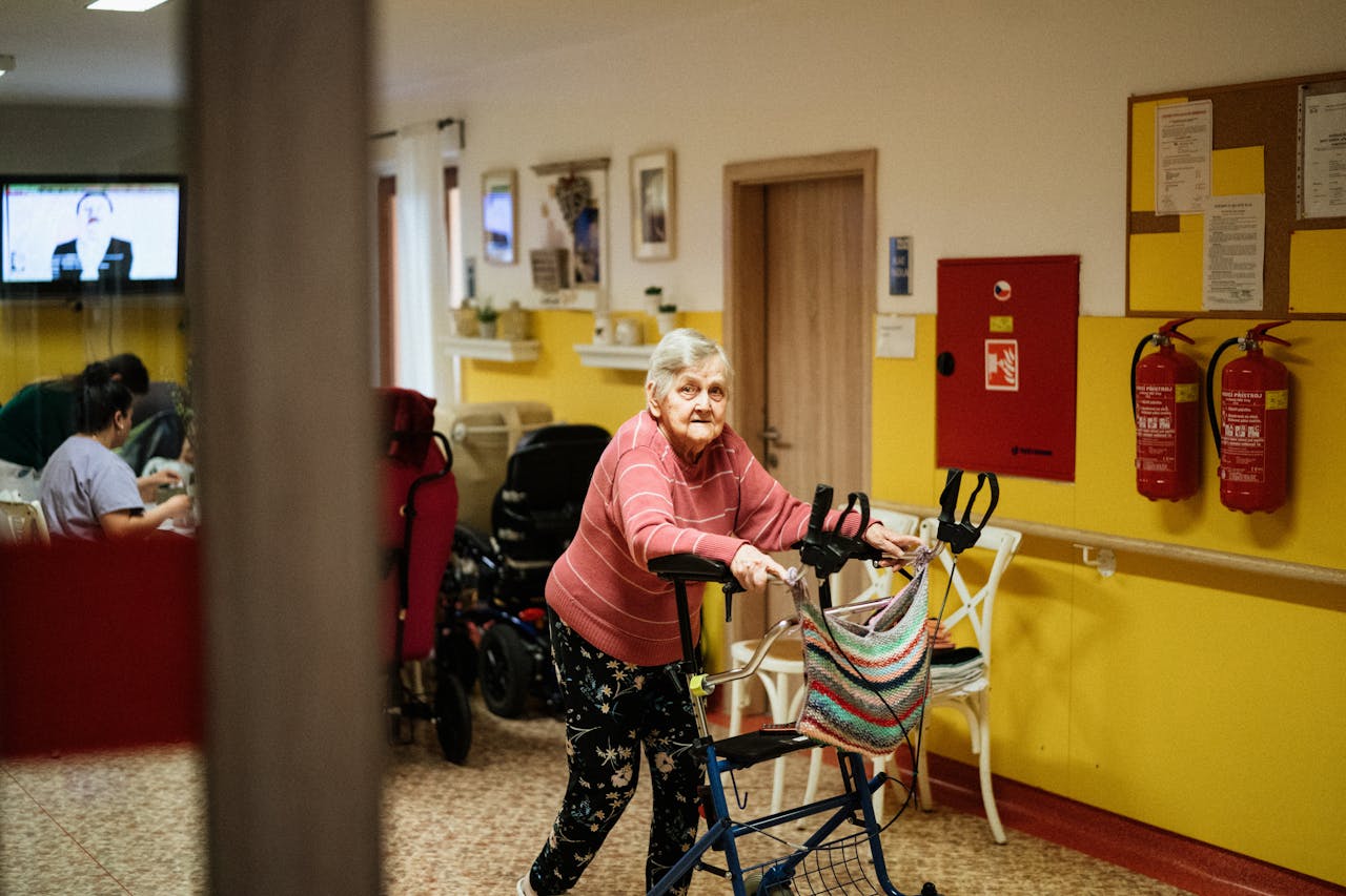 Senior woman using a walking frame in a cozy nursing home interior in Karviná, Czech Republic.
