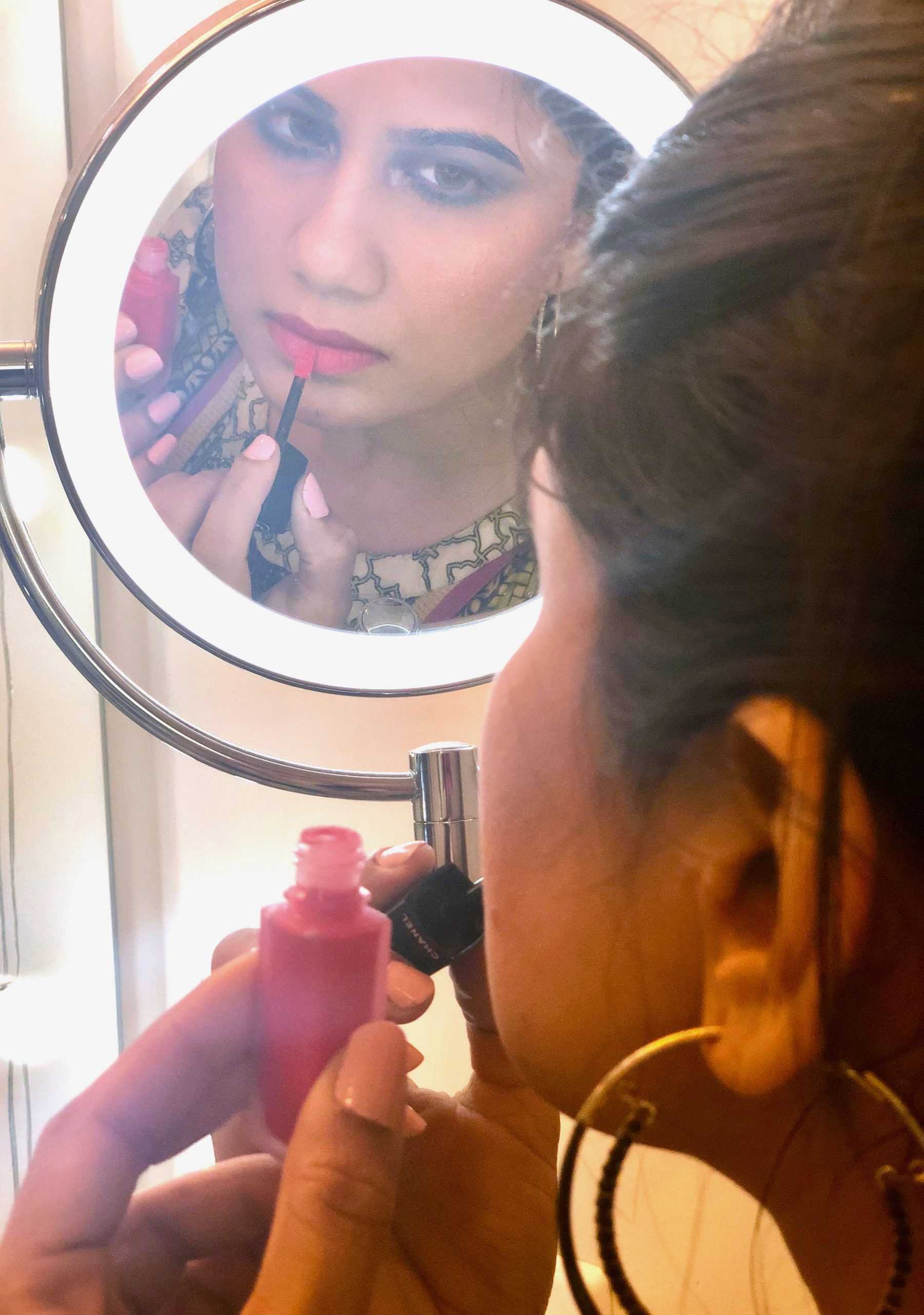 looking in mirror and applying Chanel Rouge Allure Ink shade Euphorie 