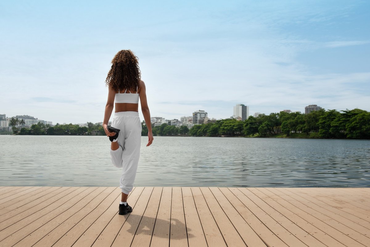 Person stretching by the water on a dock, preparing for movement and balance, symbolizing the beginning of a Gentle Reframe MAP session.