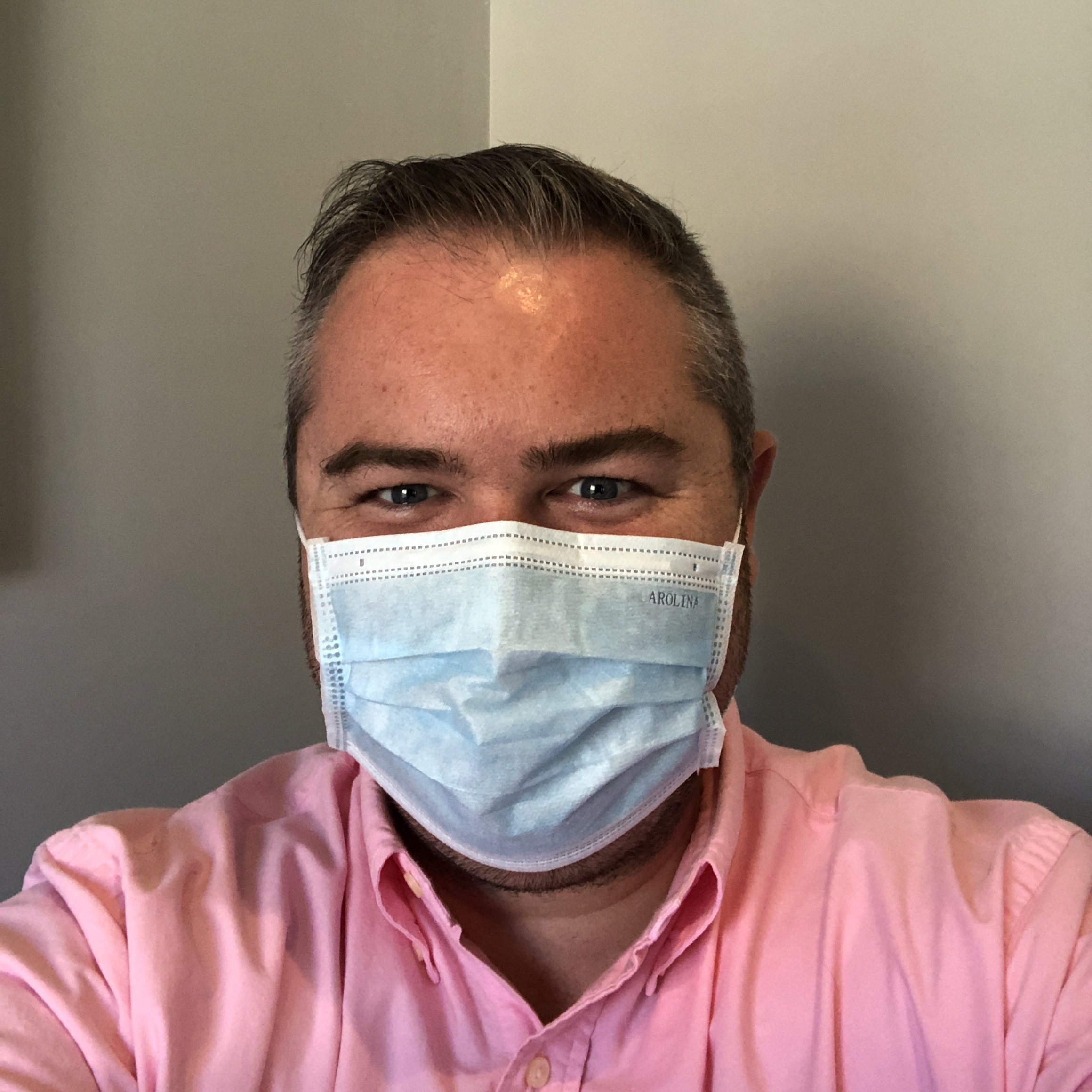 photo of me with a pink shirt on and prominent tan with a face mask on