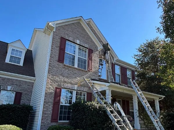 Workers maintain upper windows of a house under marvelous lights