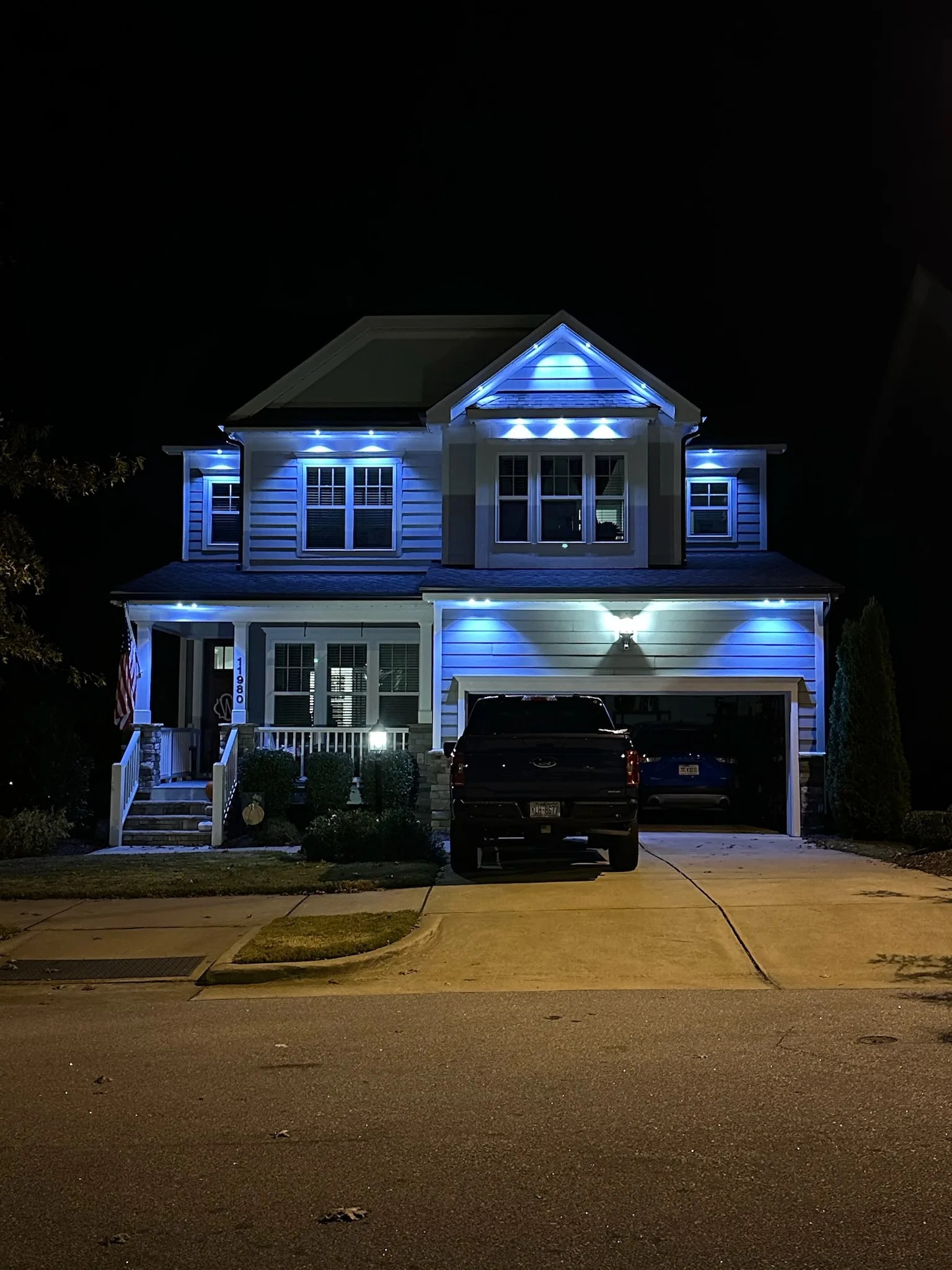 Permanent LED lights illuminate a house, creating a vibrant blue glow against the night sky
