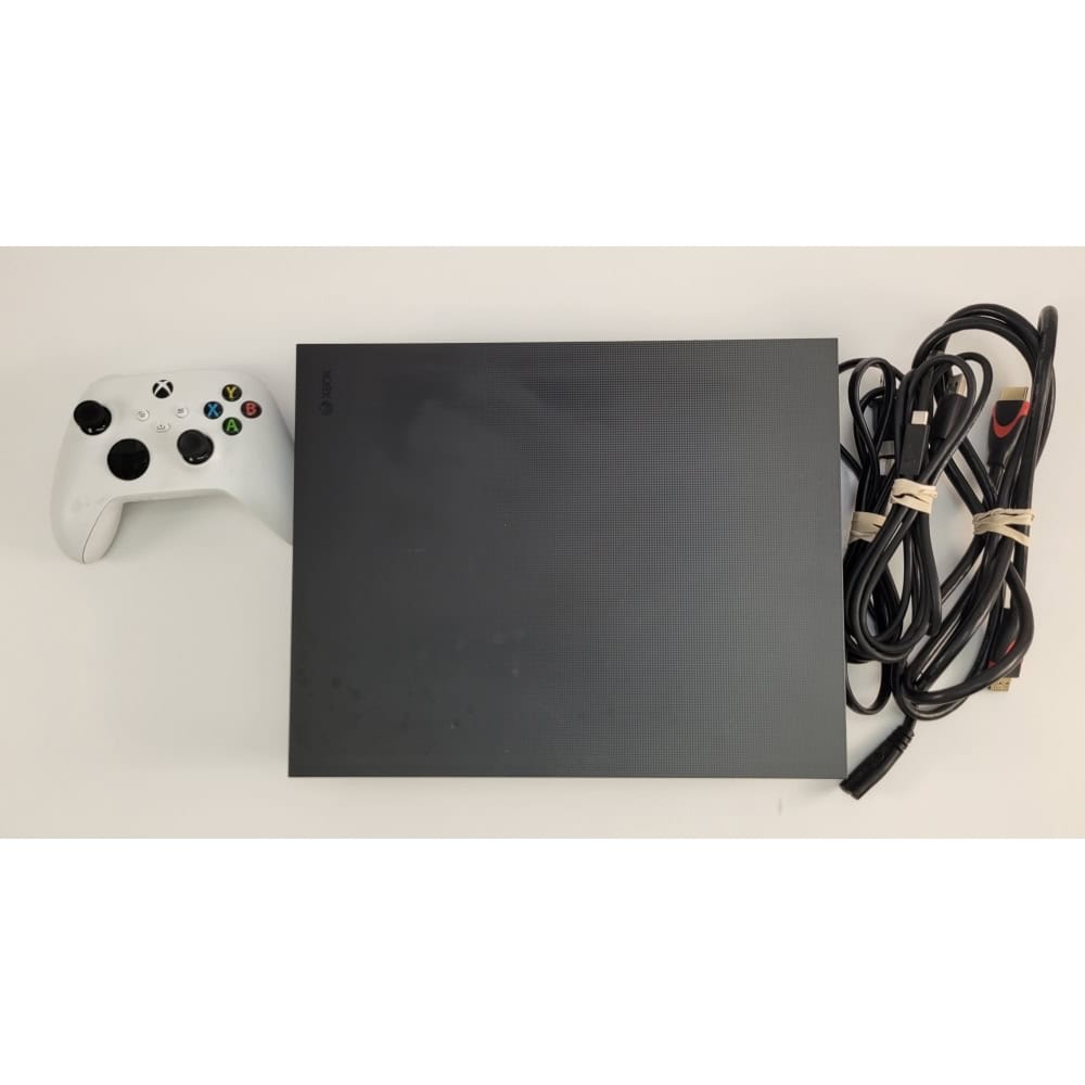 Xbox Series X gaming console with white controller and power cables on a white surface, showcasing gaming hardware setup.