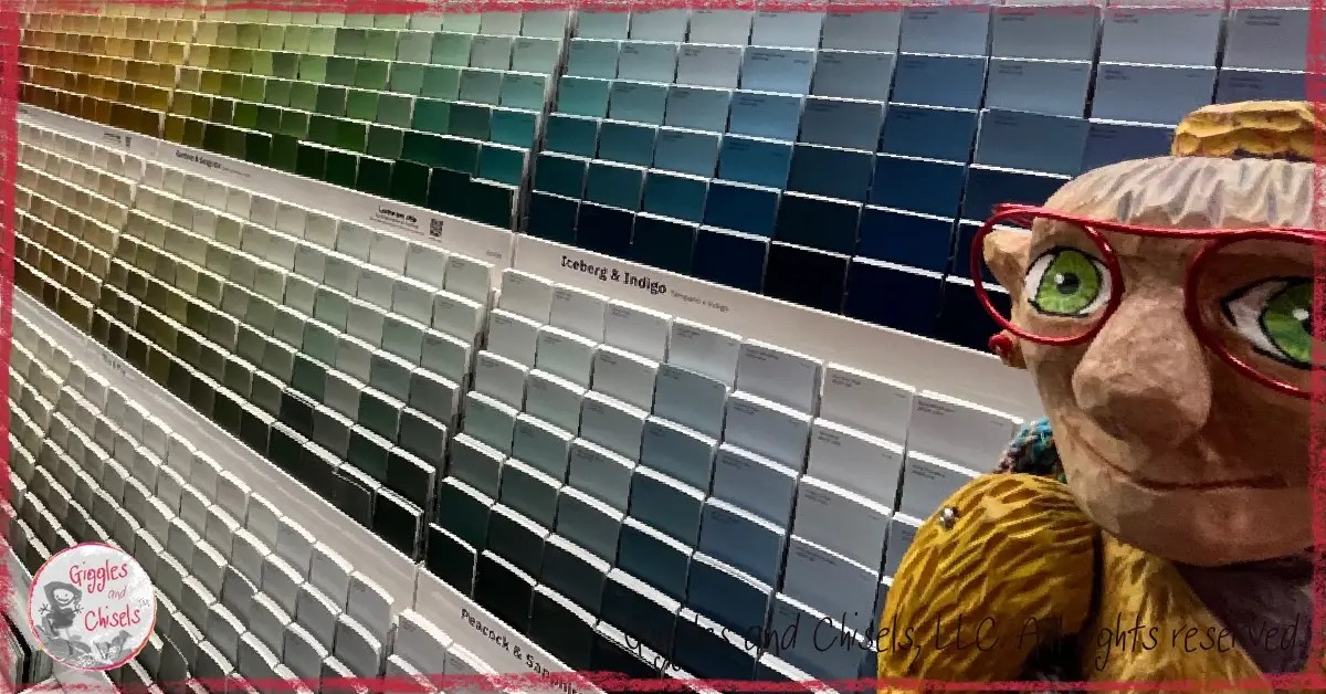 A wooden puppet, looking at samples of color paint
