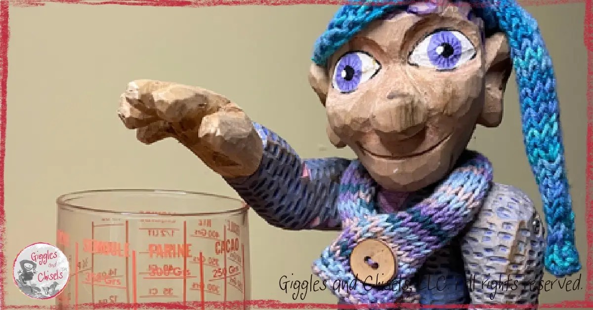A picture of Petite Clothilde, a wooden puppet, in front of a measuring cup.