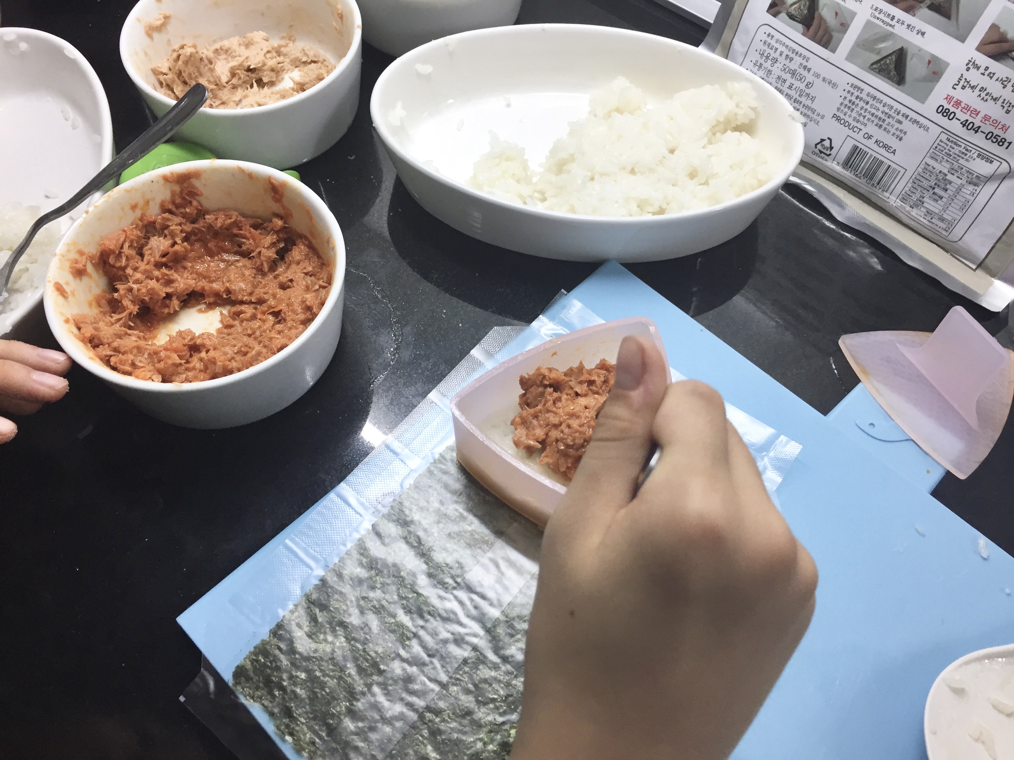 (1) layer of rice pressed into triangular mold + (2) dollop of filling placed in center...