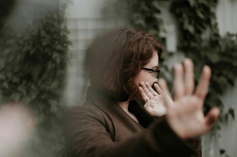 A young woman tries to hide from the camera.