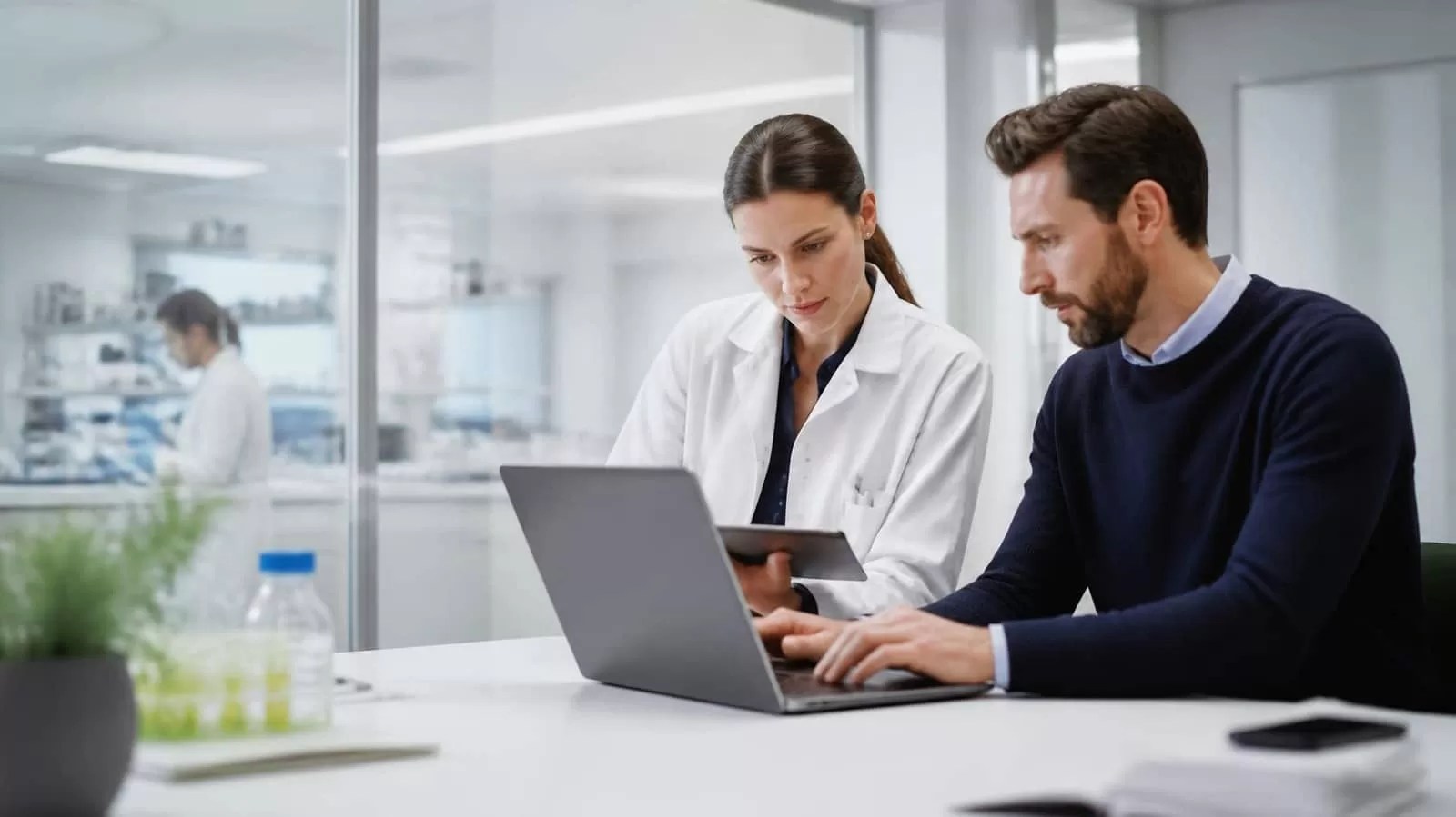Scientist and data analyst working side by side in a pharmaceutical office