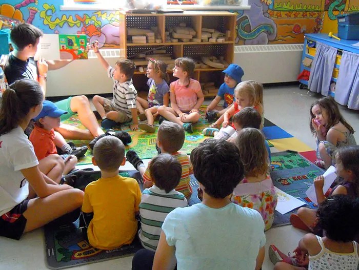 a photo of a group of children listening to a boy reading a book