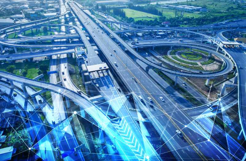 منظر جوي لتقاطع طرق سريع حديث متعدد المستويات مزود بعناصر بنية تحتية ذكية وشبكات طرق حضرية متصلة.