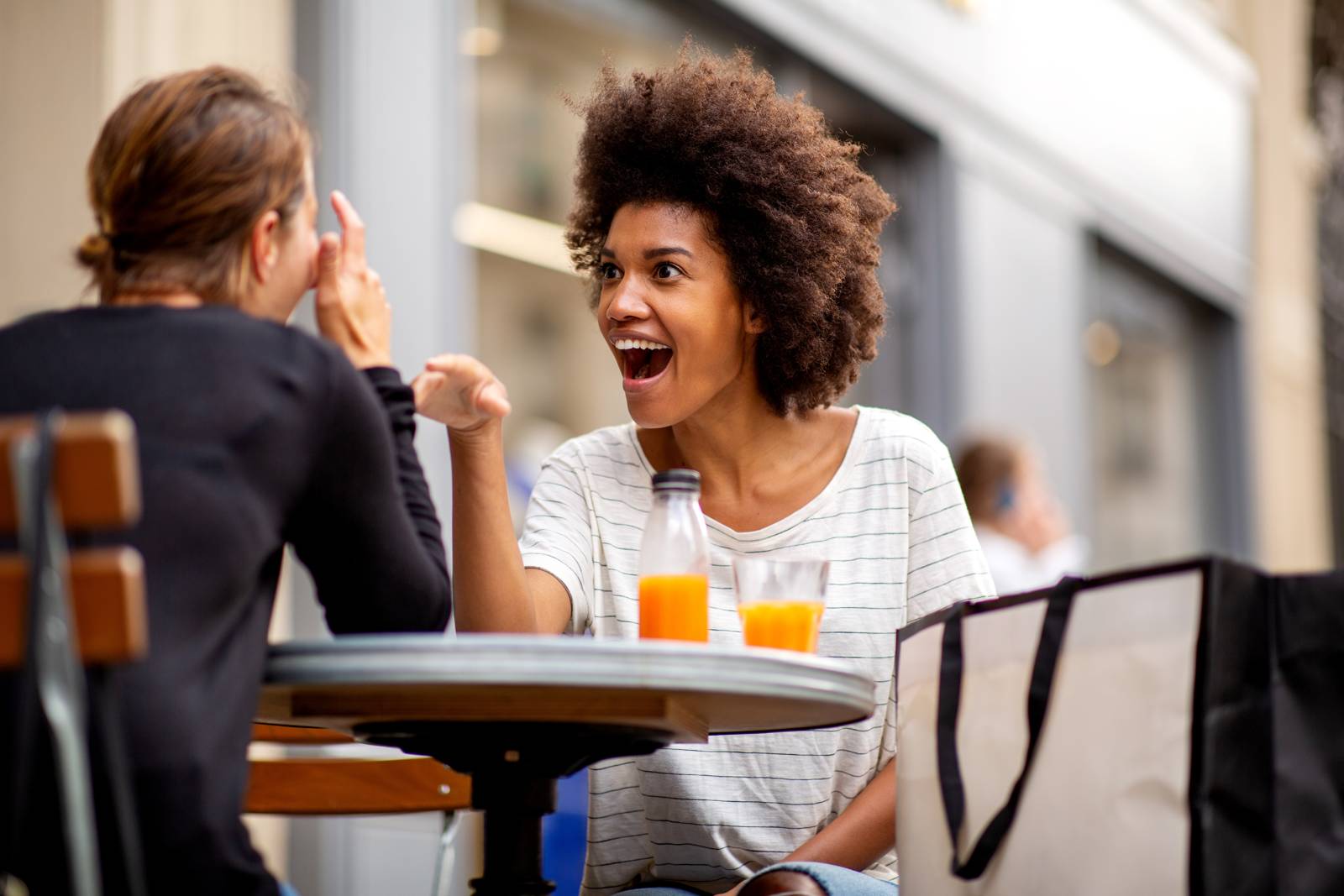 Two women laughing together over coffee, genuinely connected