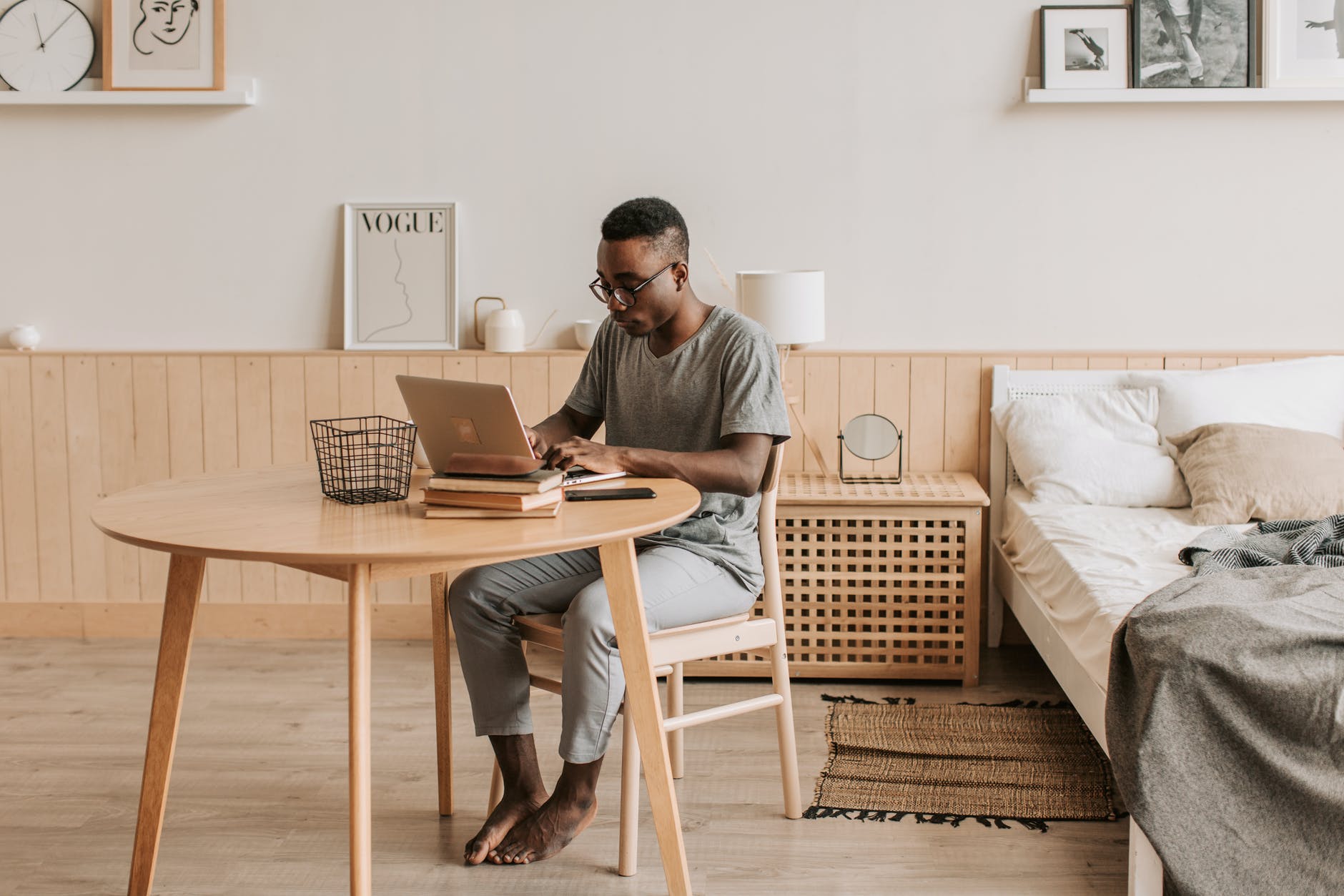 man in gray crew neck t shirt and blue denim jeans sitting on white couch using