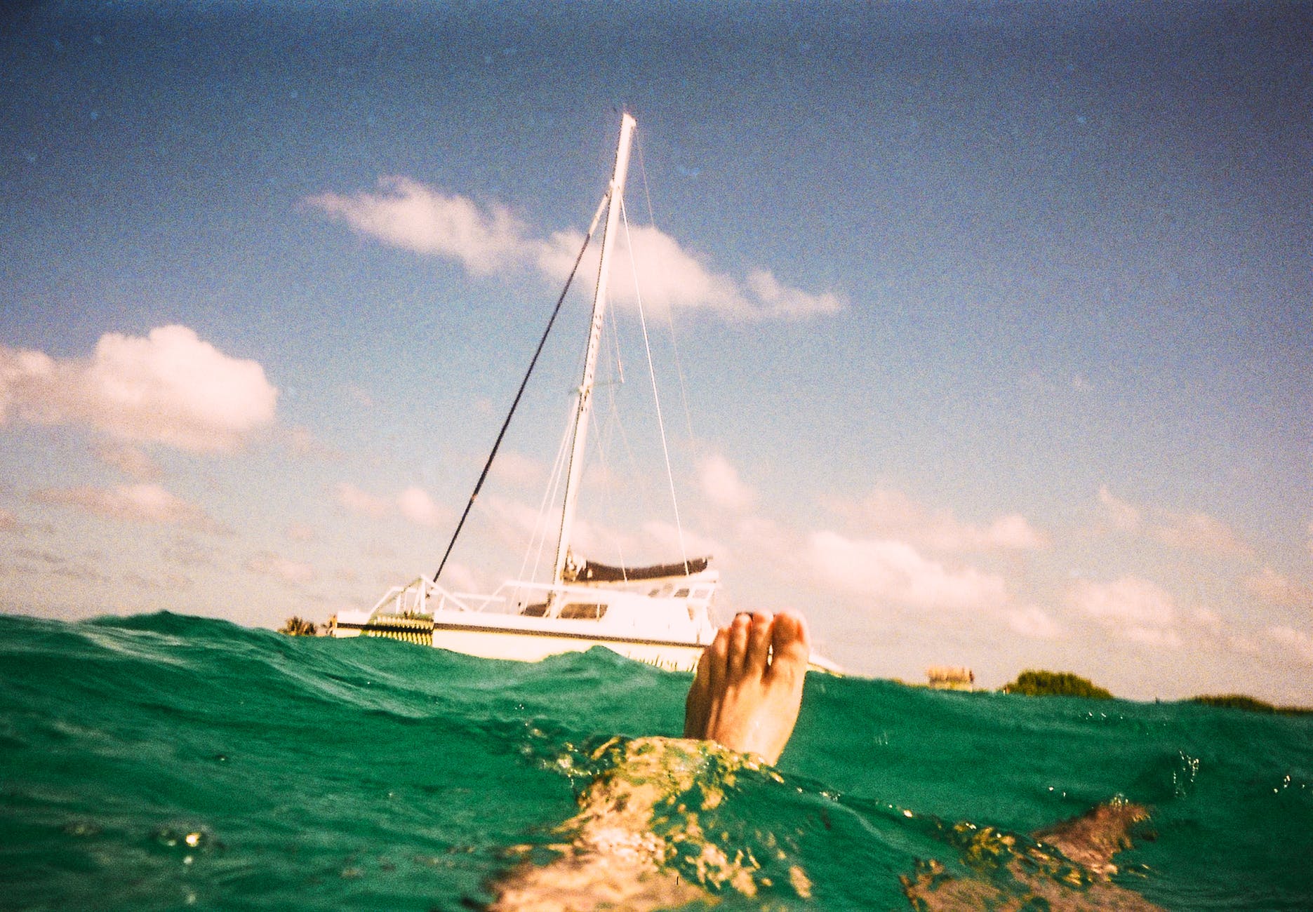 man underwater with white yacht beside