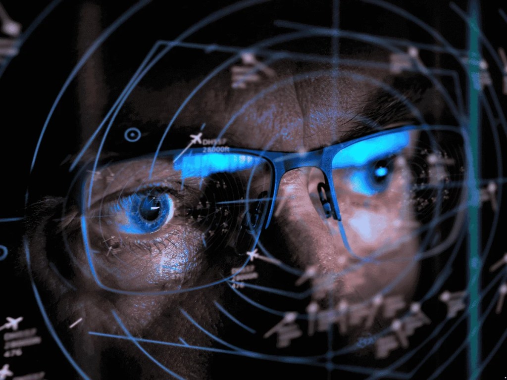 Close-up of a person wearing glasses with digital flight paths and radar data reflected over their face, symbolizing mental coordination and focus.