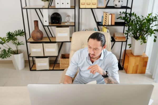 A-mature-businessman-sitting-at-a-desk-and-working-from-home-on-his-computer