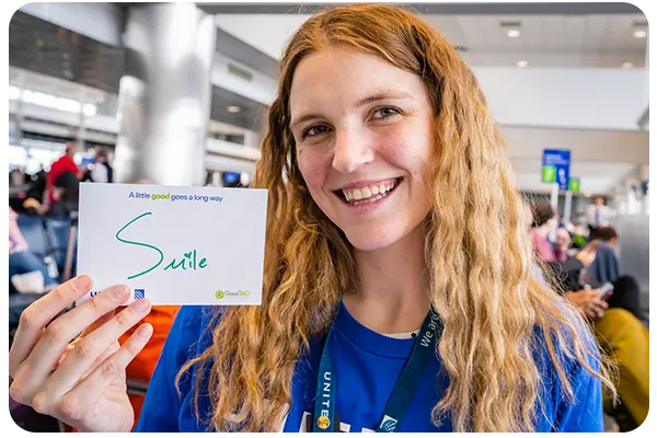 Woman holding up a "Smile" card sign