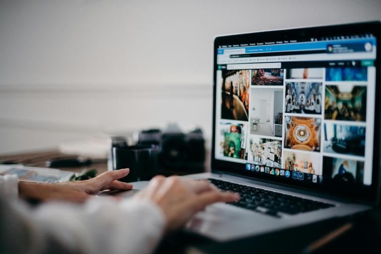 Person looking at images on a laptop, with a camera beside them
